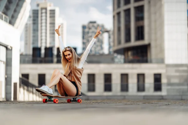 Jovem alegre sentada em um skate. — Fotografia de Stock