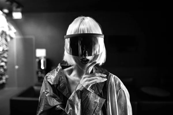 En kvinna i en futuristisk metallisk klänning med glasögon blickar framåt. — Stockfoto