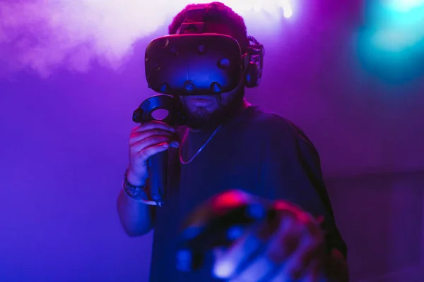 Człowiek w kasku wirtualnej rzeczywistości. Neonowy pokój z grami VR. — Zdjęcie stockowe