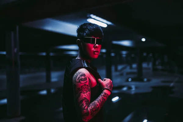 Estilo cyberpunk. Un tipo tatuado en una ciudad. Cibergafas. —  Fotos de Stock