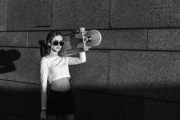 Ein schöner Strahl fällt auf eine Frau mit einem Skateboard. — Stockfoto