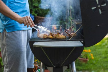 Bahçe partisi sırasında ızgara barbekü tavuk kanadı. Çatal ızgara marine et ile adam yaz açık havada