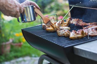 Bahçe partisi sırasında ızgara üzerinde basting fırça marine et ile el. Yaz barbekü açık havada.