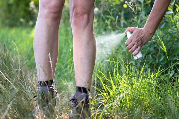 Mosquito repellent. Woman spraying insect repellent on her leg. Skin protection against tick and other insect