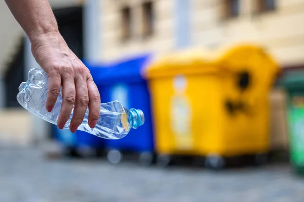 Plastik atıkların geri dönüşümü. El tutan plastik şişe. Şehir caddesindeki çöp kutusu. Çevre kavramı