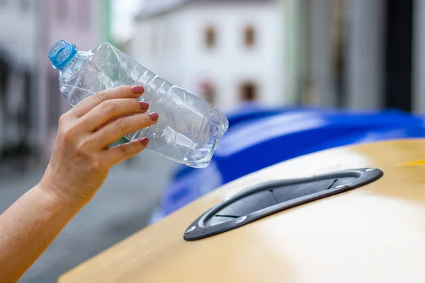 Plastik şişeyi geri dönüşüm kutusuna atan yakın çekim kadın eli. Plastik atıkile ekoloji kavramı. Çevre sorunları