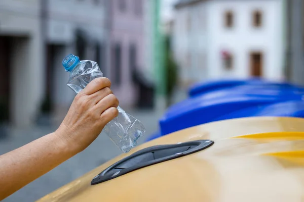 Plastik atıkların geri dönüşümü. Çöp kutusuna su şişesi atan el. Çevre sorunları