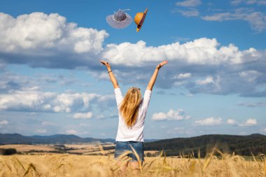 Hangisini alacağına karar veren. Güneş şapkası yakalamaya çalışan mutlu kadın. Karar ver. Yaz keyfi. 