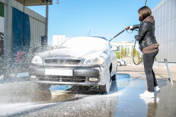 Jonge vrouw wassen auto bij selfservice carwash — Stockfoto