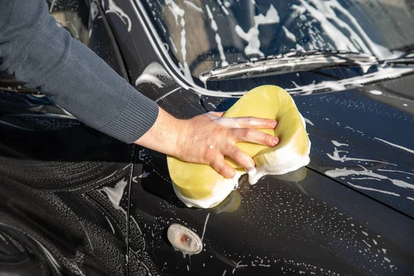 Myčka koncept. muž auto umýt mýdlem a žlutá houba — Stock fotografie