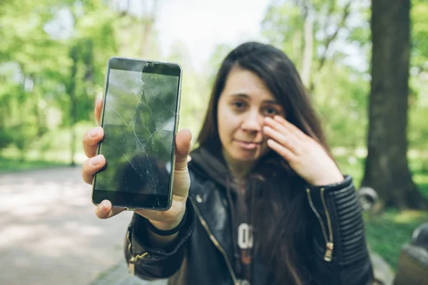 Muda sedih wanita dewasa menunjukkan telepon retak — Stok Foto