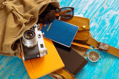 malzeme ile sırt çantası. seyahat kavramı. pasaport para güneş gözlüğü mavi ahşap zemin üzerine