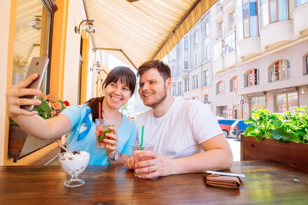 Coppia seduta in caffè in giorno d'estate prendendo selfie. bevande fresche — Foto Stock