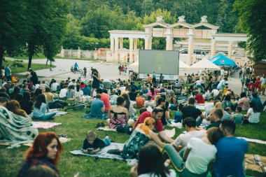 Lviv, Ukrayna - 1 Haziran 2018: Şehir Parkı açık hava sinema film izlerken çim üzerinde oturan insanlar