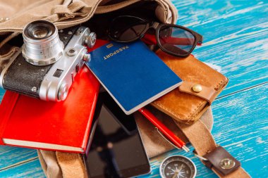 malzeme ile sırt çantası. seyahat kavramı. pasaport para güneş gözlüğü mavi ahşap zemin üzerine