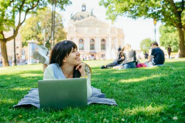 yeşil çimenlerin üzerinde Şehir Parkı içinde laptop ile döşeme Genç Yetişkin kadın