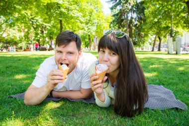paket üzerinde oturan ve dondurma yemek Şehir Parkı'yaz gün içinde bir çift