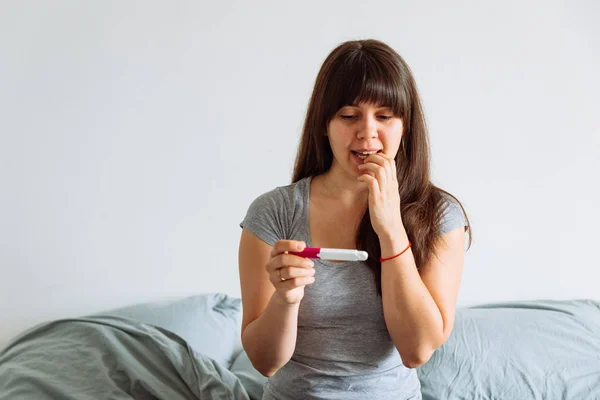 Kvinna Med Orolig Visa Tittar Graviditetstest Sittande Sängen — Stockfoto