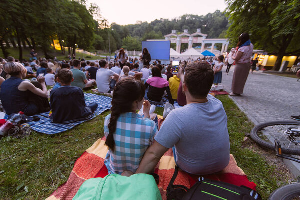people watching movie in open air cinema in city park