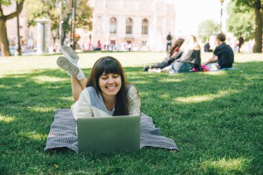 yeşil çimenlerin üzerinde Şehir Parkı içinde laptop ile döşeme Genç Yetişkin kadın