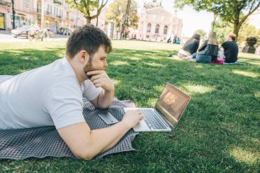 yaz günü şehir parkı içinde laptop üzerinde genç yetişkin adam