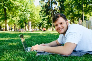 yaz günü şehir parkı içinde laptop üzerinde genç yetişkin adam