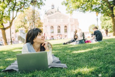 yeşil çimenlerin üzerinde Şehir Parkı içinde laptop ile döşeme Genç Yetişkin kadın