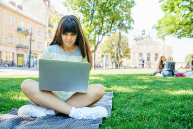 yeşil çimenlerin üzerinde Şehir Parkı içinde laptop ile döşeme Genç Yetişkin kadın