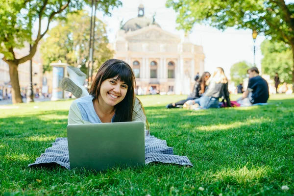 yeşil çimenlerin üzerinde Şehir Parkı içinde laptop ile döşeme Genç Yetişkin kadın