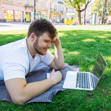 yaz günü şehir parkı içinde laptop üzerinde genç yetişkin adam