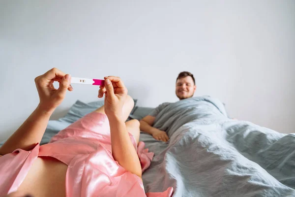 point of view. woman looking on positive pregnancy test. man slipping on background