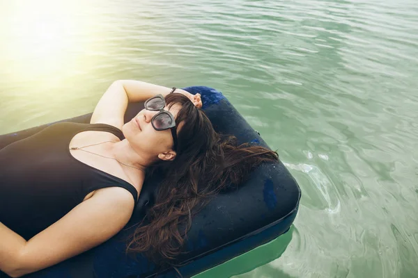 woman on mattress swimming in azure water. summer time concept