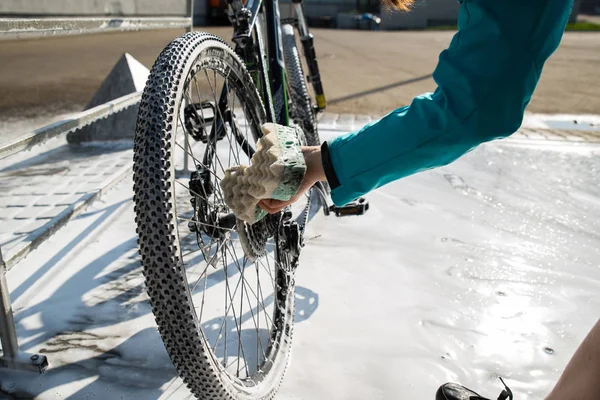 woman hand cleaning bicycle wheel with sponge.