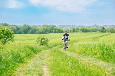 adam yeşil arpa alanındaki iz sürme bisikletle. kopya alanı