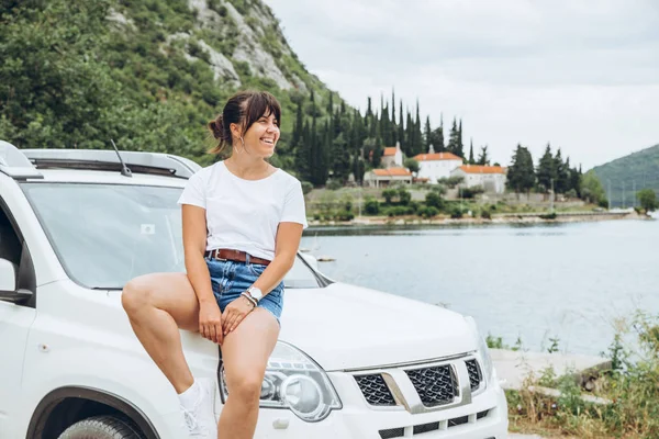 Donna Seduta Sul Cofano Dell Auto Mare Montagne Sullo Sfondo — Foto Stock