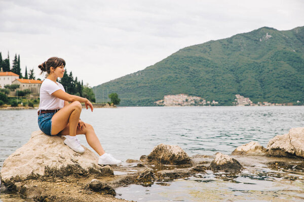 woman sitting on cliff and looking at sea. travel concept