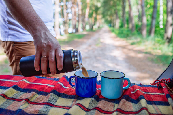 man hand pour on coffee into metal cups from thermos bottle. copy space