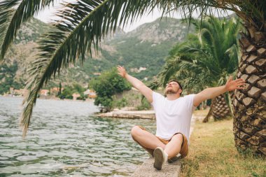 deniz kenarında güzel görünümü ile oturan adam. arka planda dağlar. Yaz saati