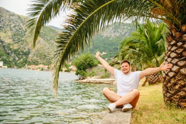 deniz kenarında güzel görünümü ile oturan adam. arka planda dağlar. Yaz saati
