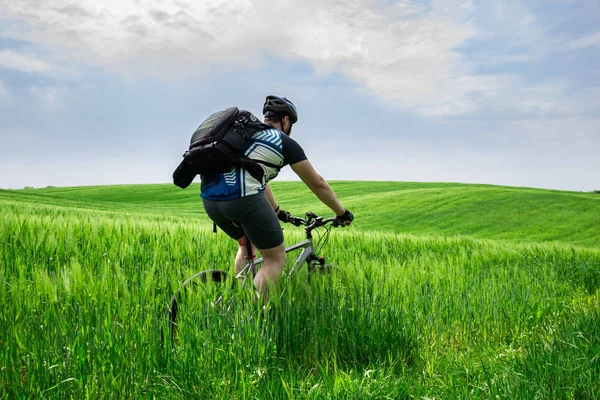 緑のフィールドで強力な若者乗馬自転車 — ストック写真