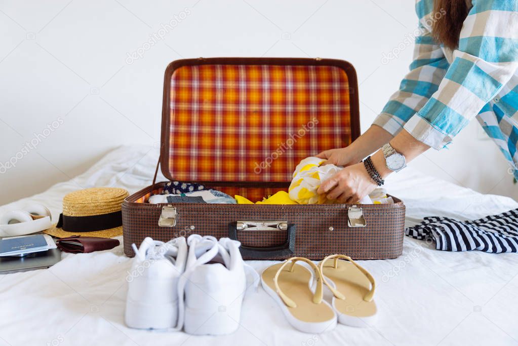 woman hands with watch put clothes in suitcase. travel concept. copy space