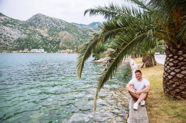 deniz kenarında güzel görünümü ile oturan adam. arka planda dağlar. Yaz saati