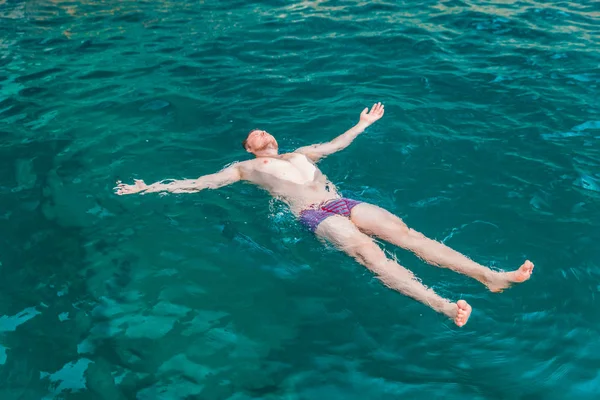 man swimming on back in blue transparent sea water. summer vacation