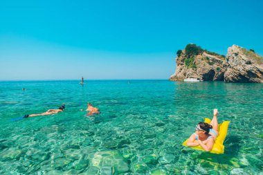 sarı şişme yatak genç güzel kadın. insanlar açık suda yüzmek. yaz tatili