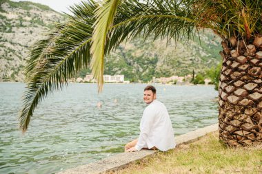 deniz kenarında güzel görünümü ile oturan adam. arka planda dağlar. Yaz saati