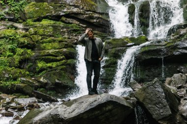 arka plan üzerinde şelale ile kayaya oturan adam. seyahat kavramı