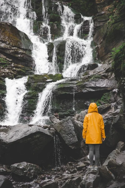 Frau Steht Gelbem Regenmantel Und Blickt Auf Wasserfall Wanderkonzept — Stockfoto