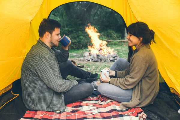 couple resting in tent with view on fire. hiking concept