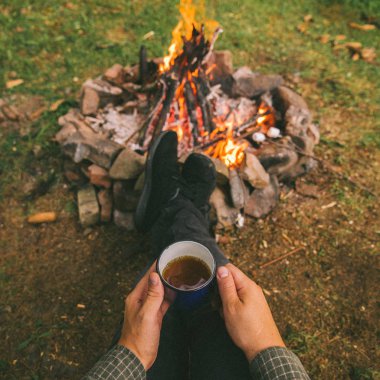 ilk bakış. kamp ateşi yakınındaki metal fincan çay içme adam. Hiking