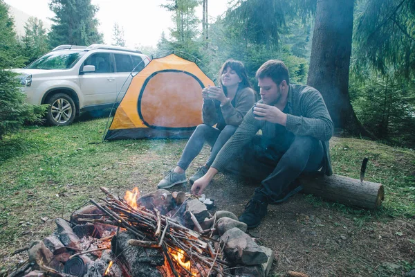 Paar Sitzt Lagerfeuer Und Trinkt Tee Zelt Und Geländewagen Hintergrund — Stockfoto
